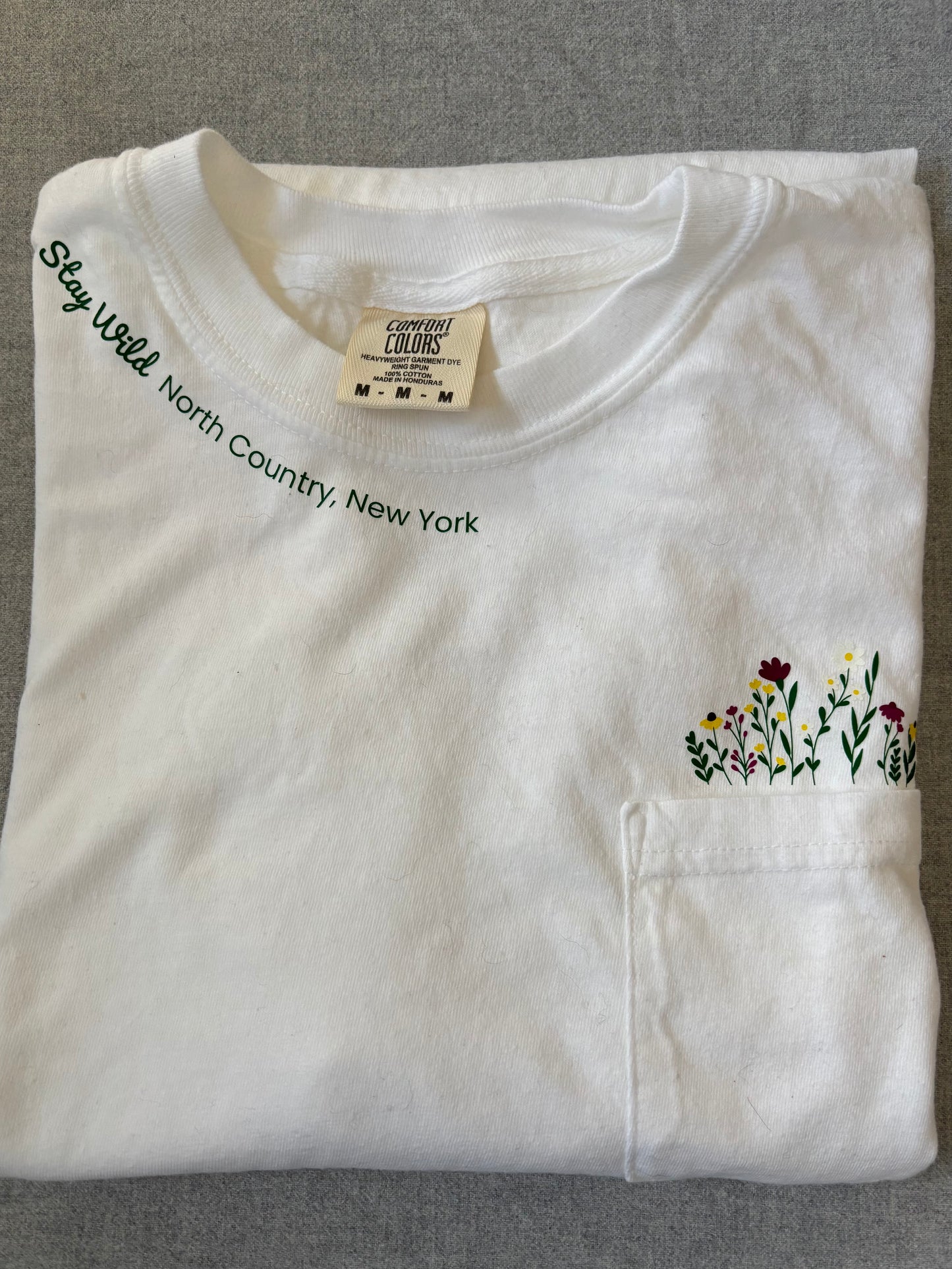 Stay Wild North Country New York Pocket Tee – White Comfort Colors Shirt with Wildflower Design