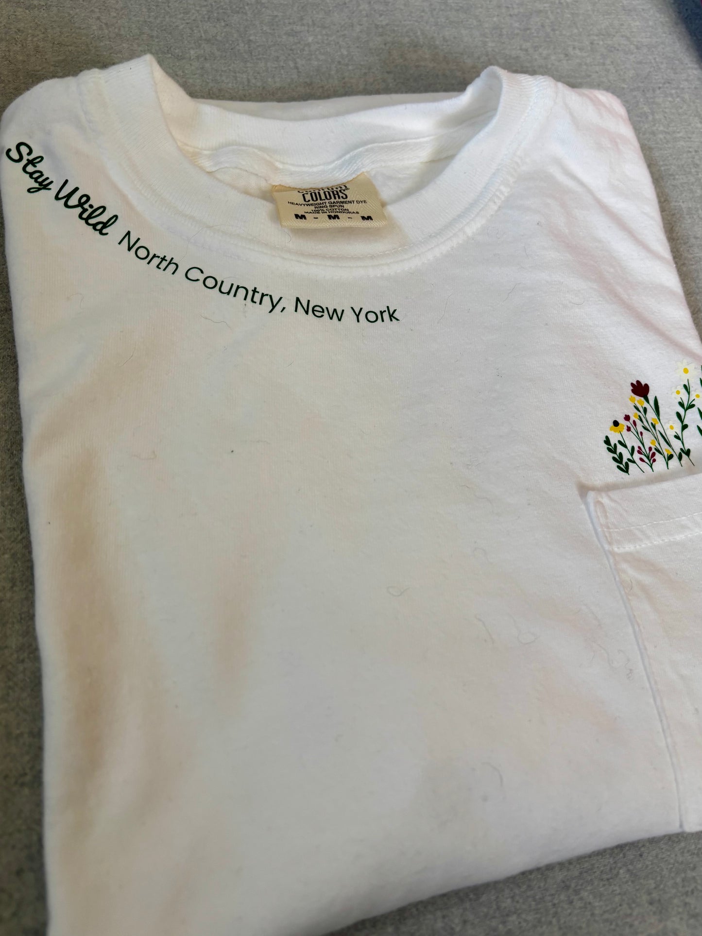 Stay Wild North Country New York Pocket Tee – White Comfort Colors Shirt with Wildflower Design