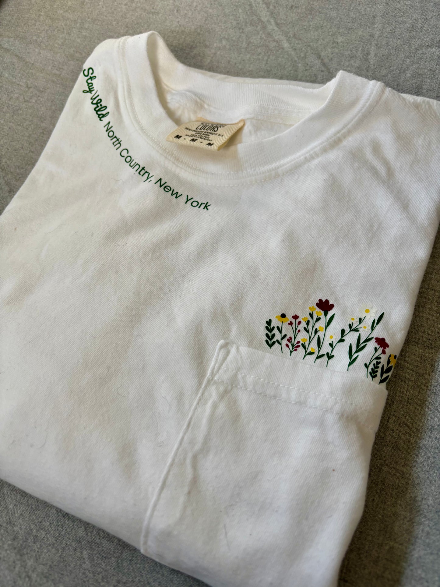 Stay Wild North Country New York Pocket Tee – White Comfort Colors Shirt with Wildflower Design
