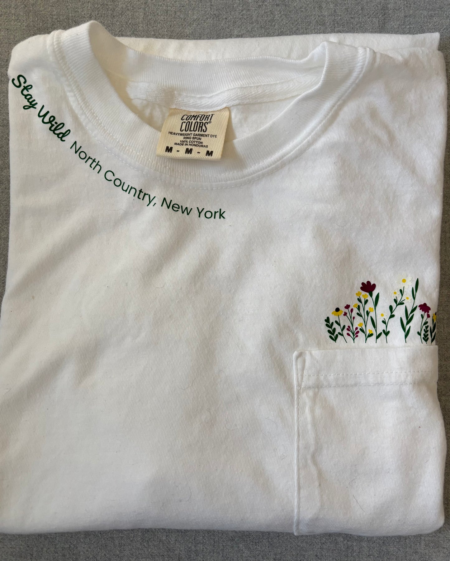 Stay Wild North Country New York Pocket Tee – White Comfort Colors Shirt with Wildflower Design